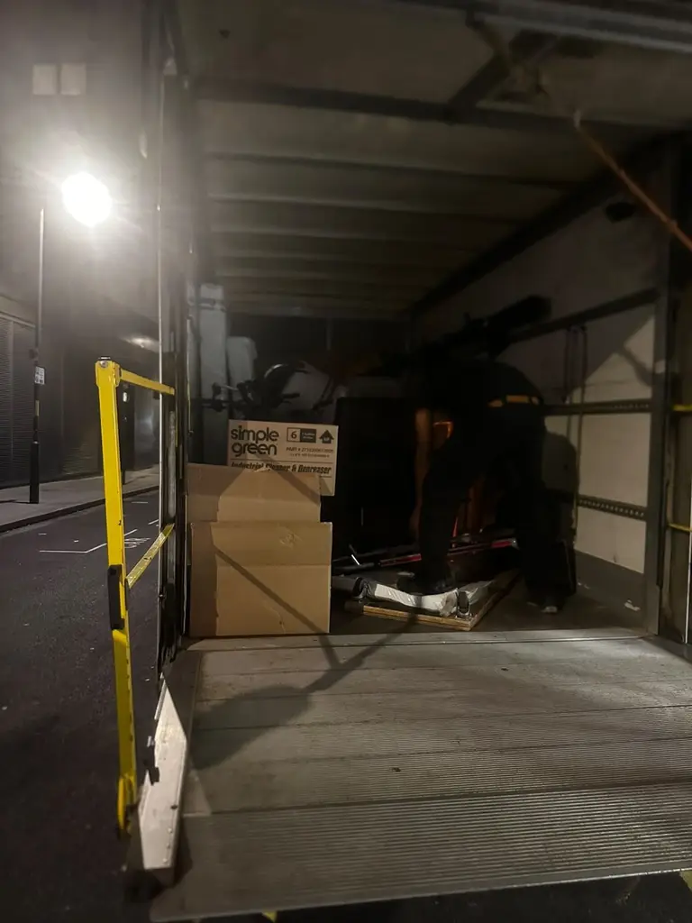 2FAST van with its tail lift lowered, being loaded on a London street after dark