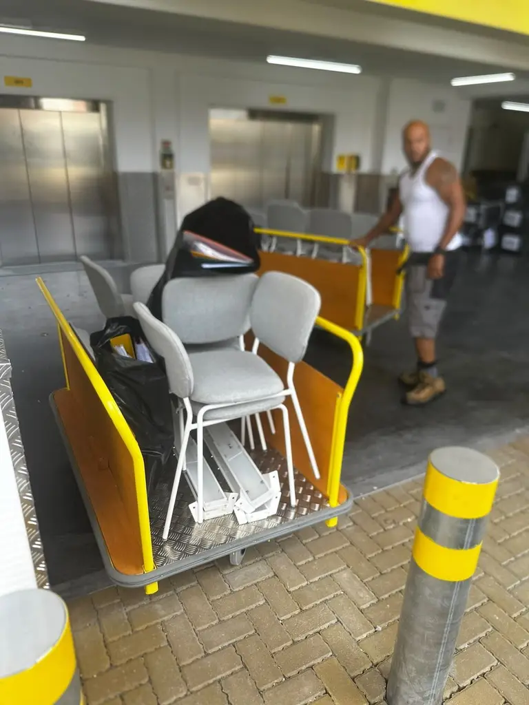 2FAST mover wheeling a trolley of office chairs out of a commercial building