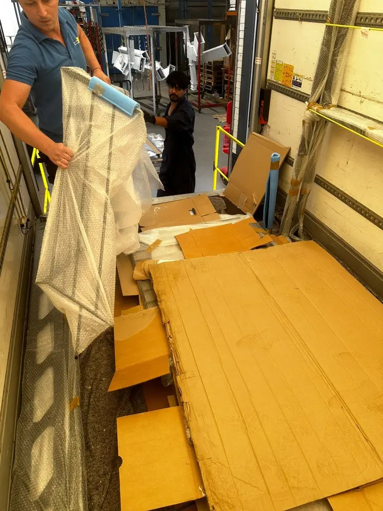 2FAST team member lifting wrapped panels from a van at a commercial loading bay