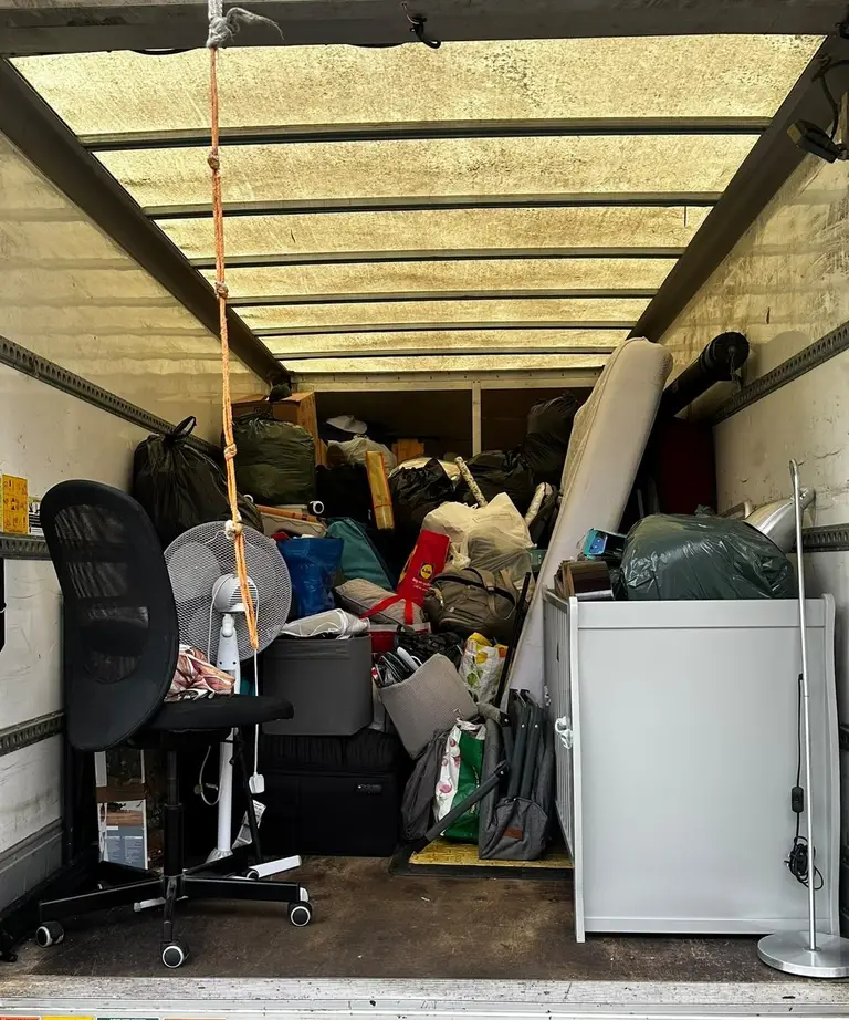 Inside a 2FAST removals van loaded with a household move: office chair, bags, boxes and a cabinet secured for transport
